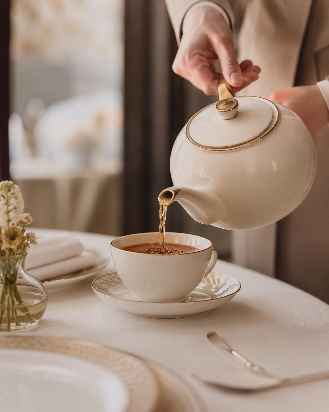 Service du thé versé dans une tasse en porcelaine à filet doré